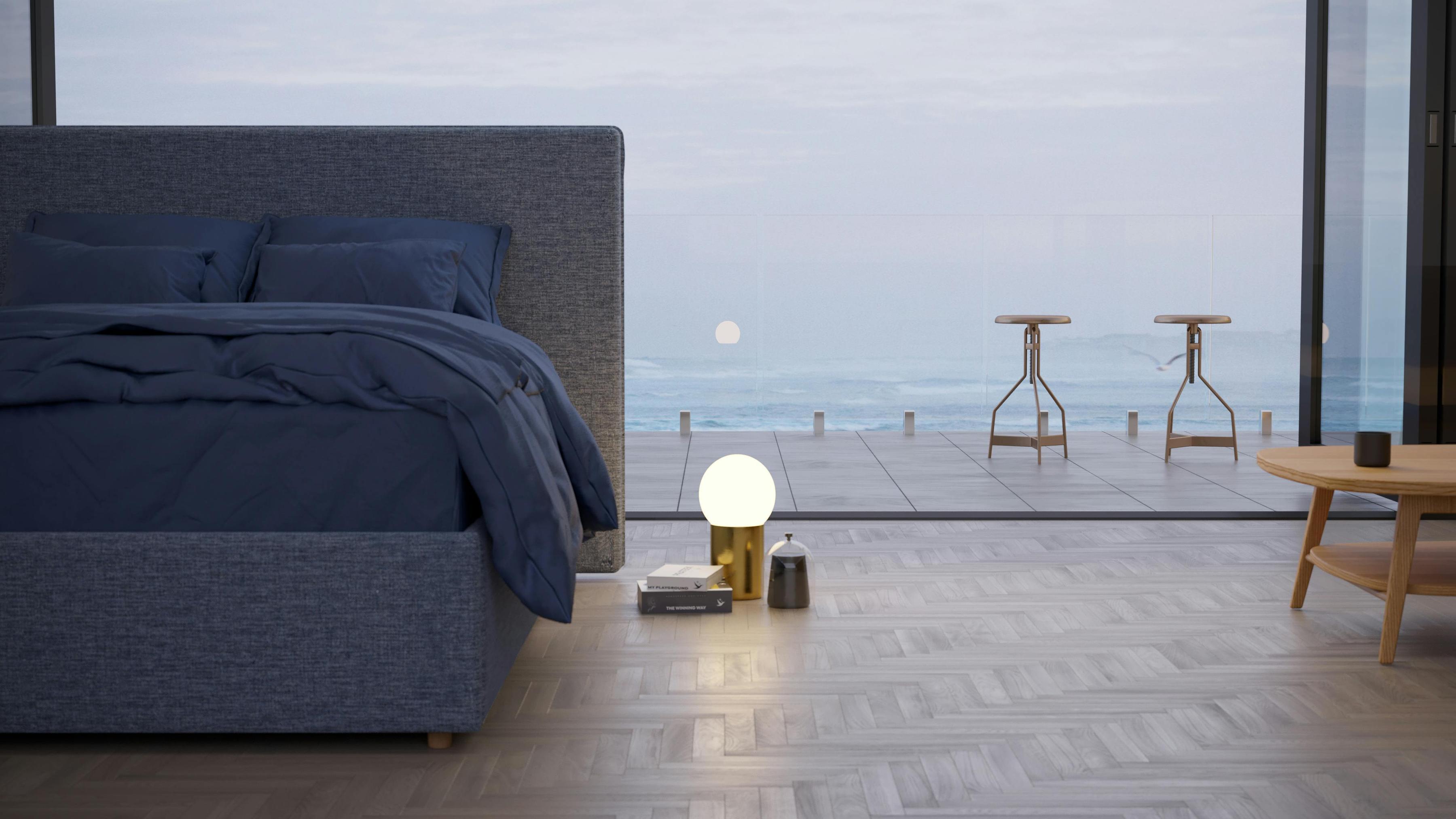 The Seaspray SD Indestruct Bed in Washed Navy, in a minimalist bedroom overlooking the ocean as the sun rises.