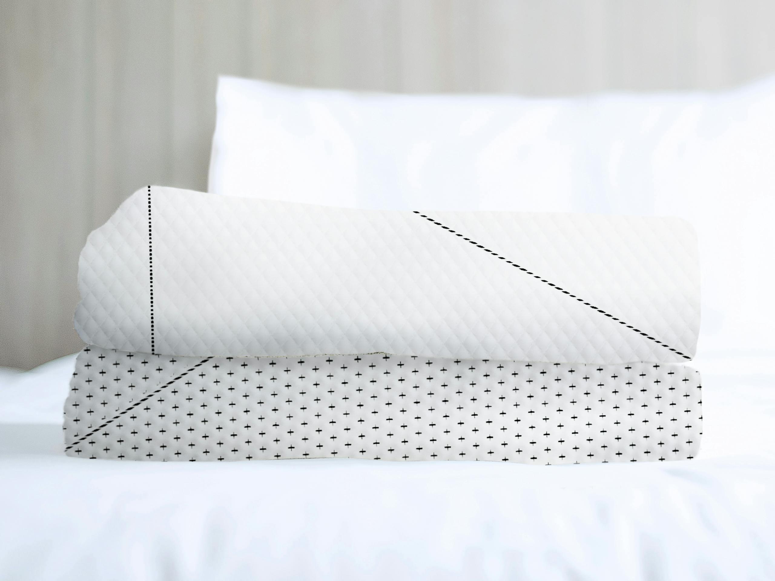 A BreatheTech cover folded and sitting on a white bed