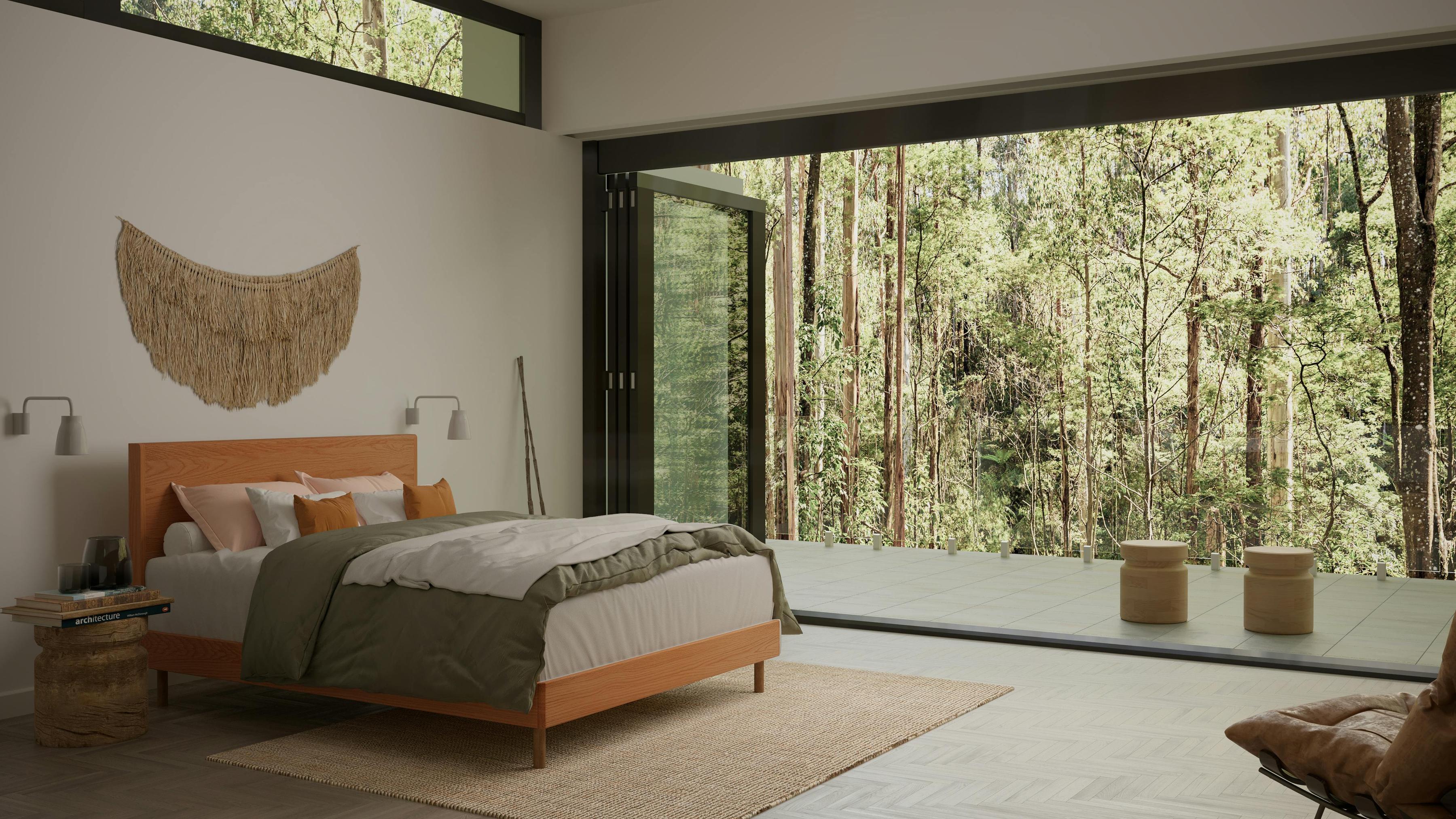The Baker SD Indestruct Bed in European Oak, in a contemporary bedroom with organic accent decor, overlooking a lush Australian forest.